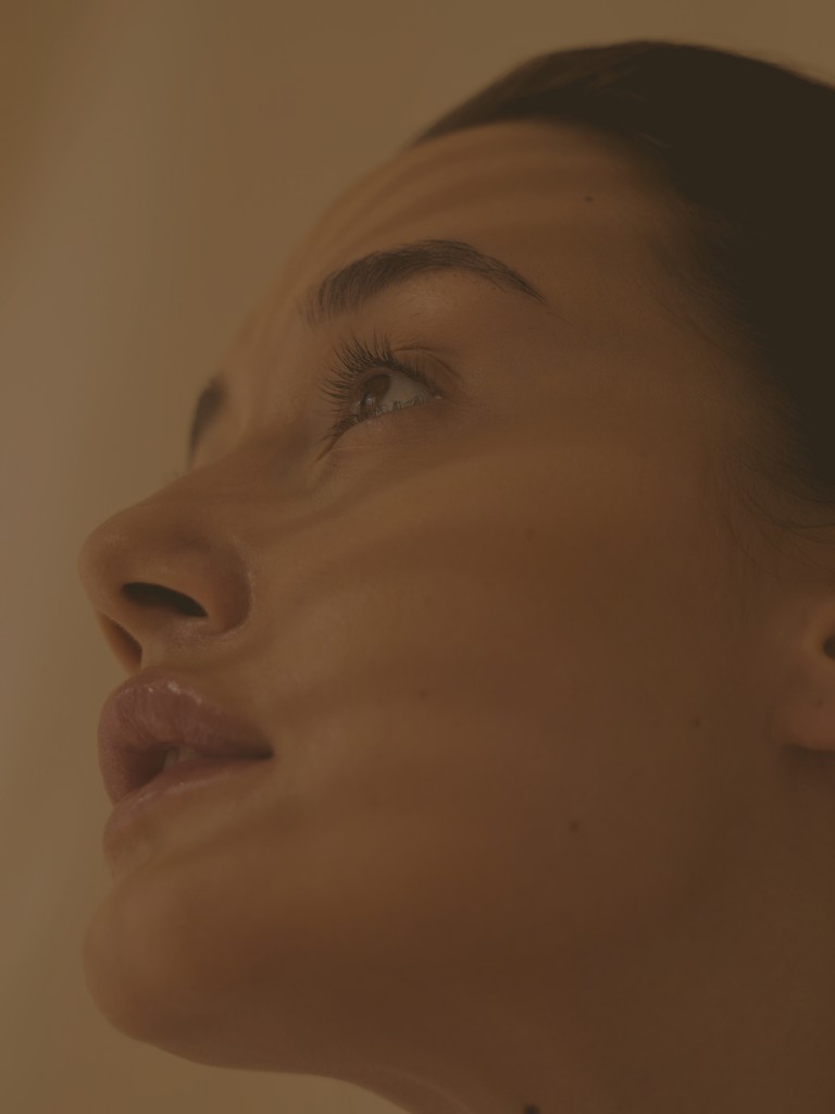 Close-up portrait of a woman looking upward in warm, soft light