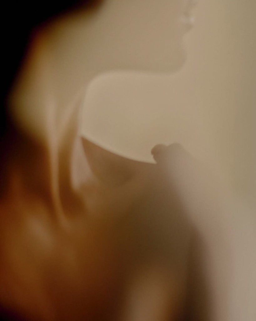 Soft-focus portrait of a woman's shoulder and neckline in warm, diffused light